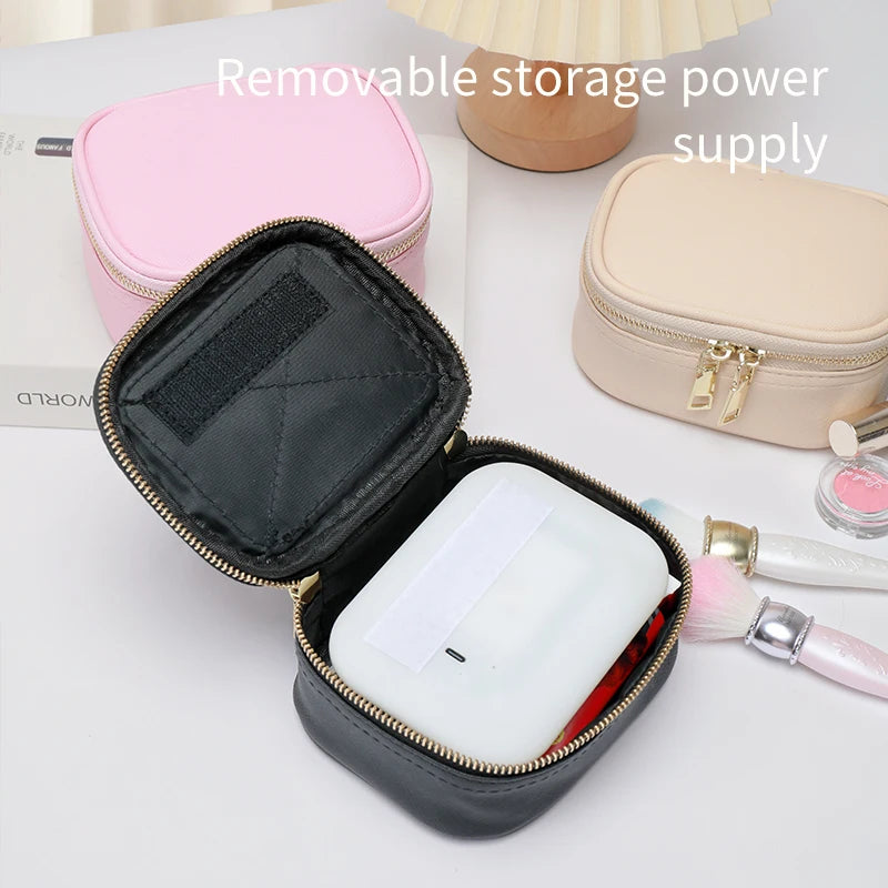 Black storage case with a white power bank inside, on a surface with cosmetic items.