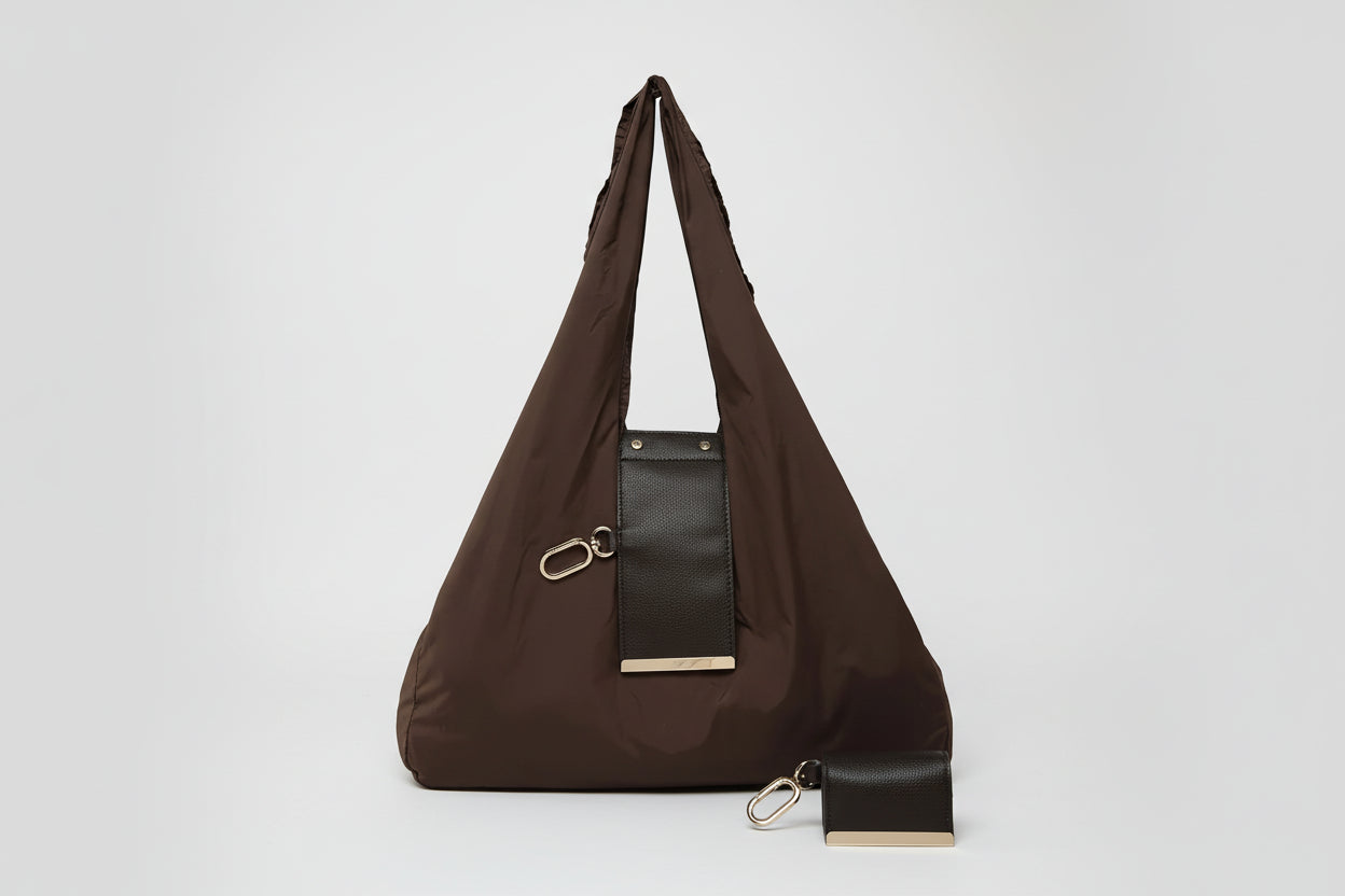 Brown shoulder bag with a black patch and gold accents on a white background