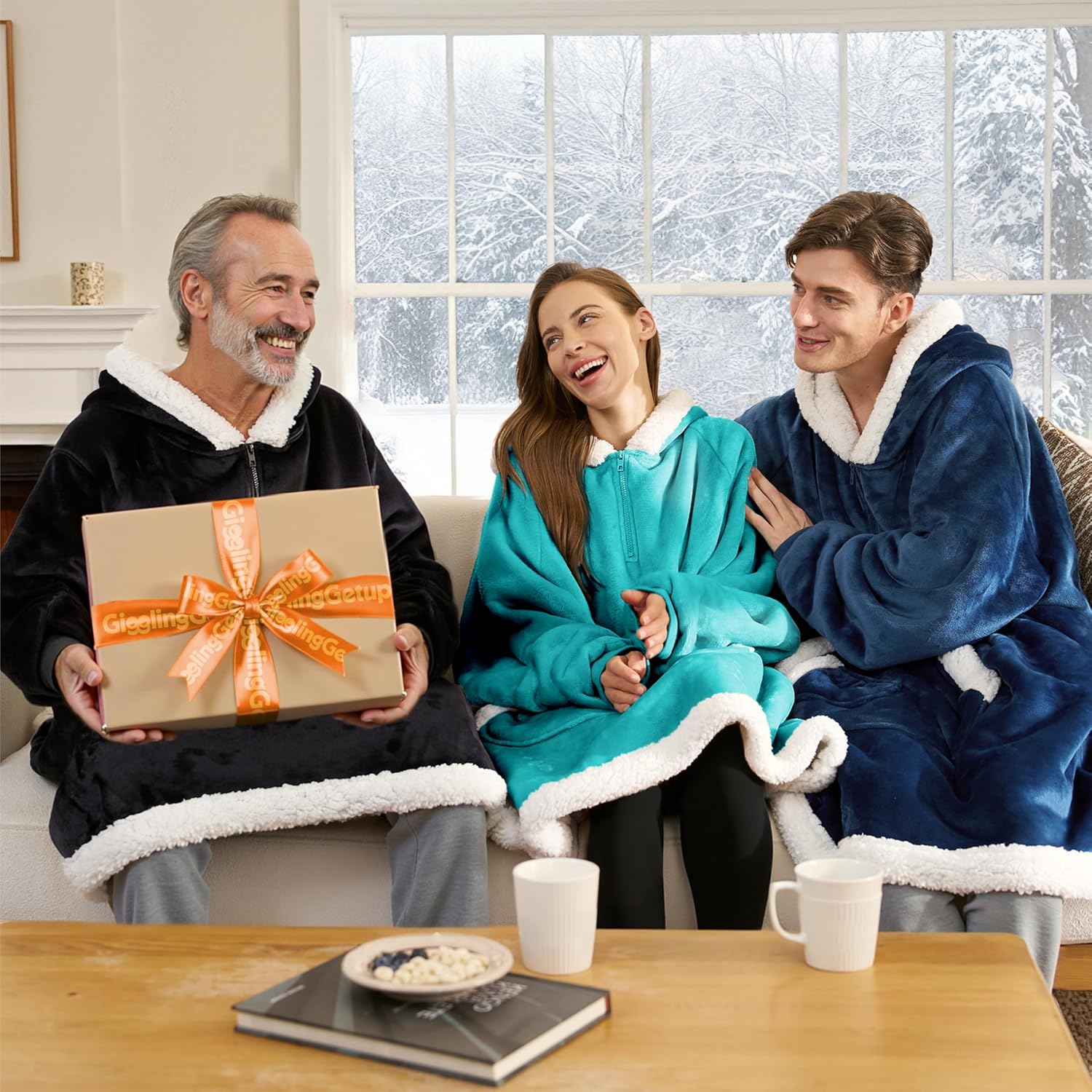 Product image of CozyNest wearable blanket hoodie for home loungingThree people in cozy robes sitting together with a gift in a snowy outdoor setting.
