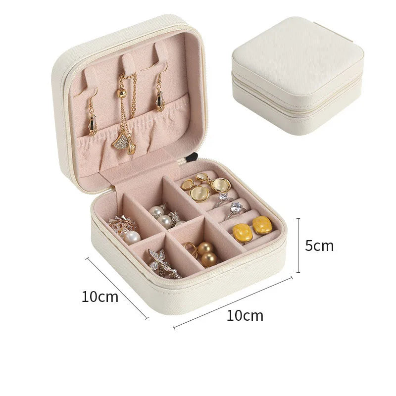 Beige jewelry box with compartments containing earrings and buttons, open on a white background.