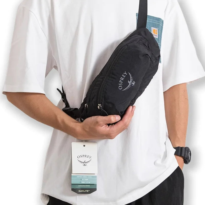 Product image of Person holding a black Osprey waist bag with a visible tag on a white background