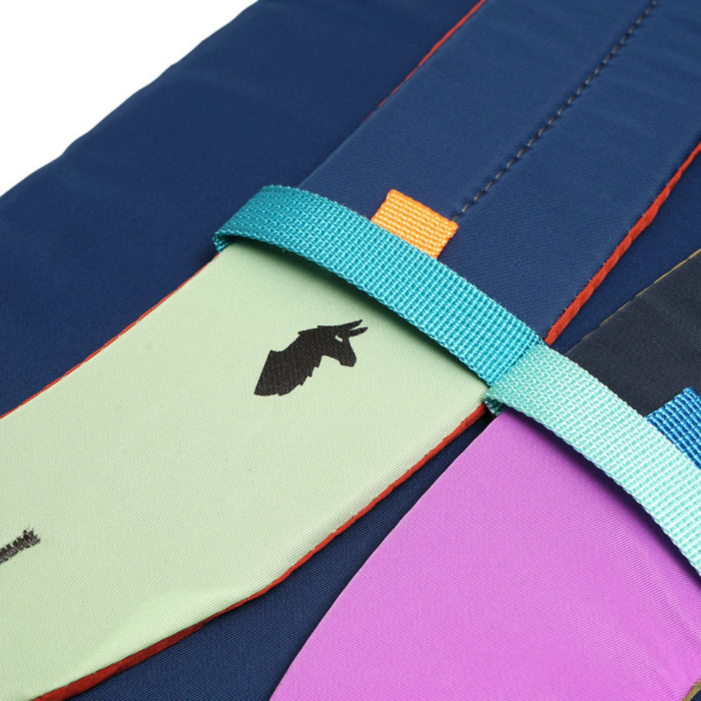 Close-up of a colorful fabric with a blue strap and a small logo - travel gear