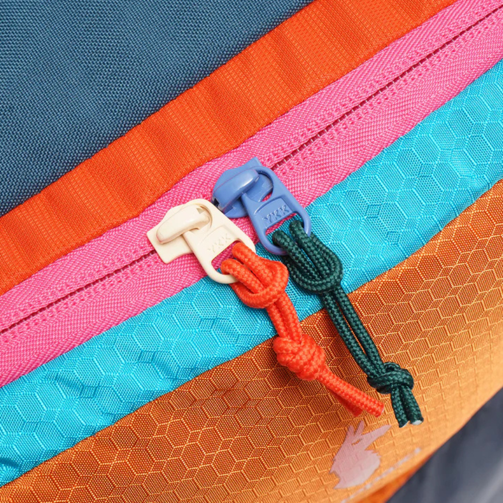 Close-up of colorful zippers on a textured fabric background - travel luggage