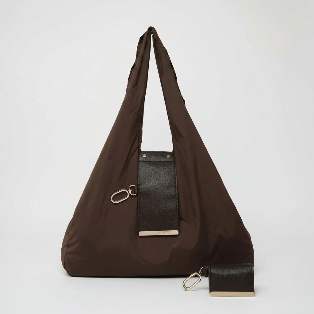 Brown shoulder bag with a black patch and gold accents on a white background