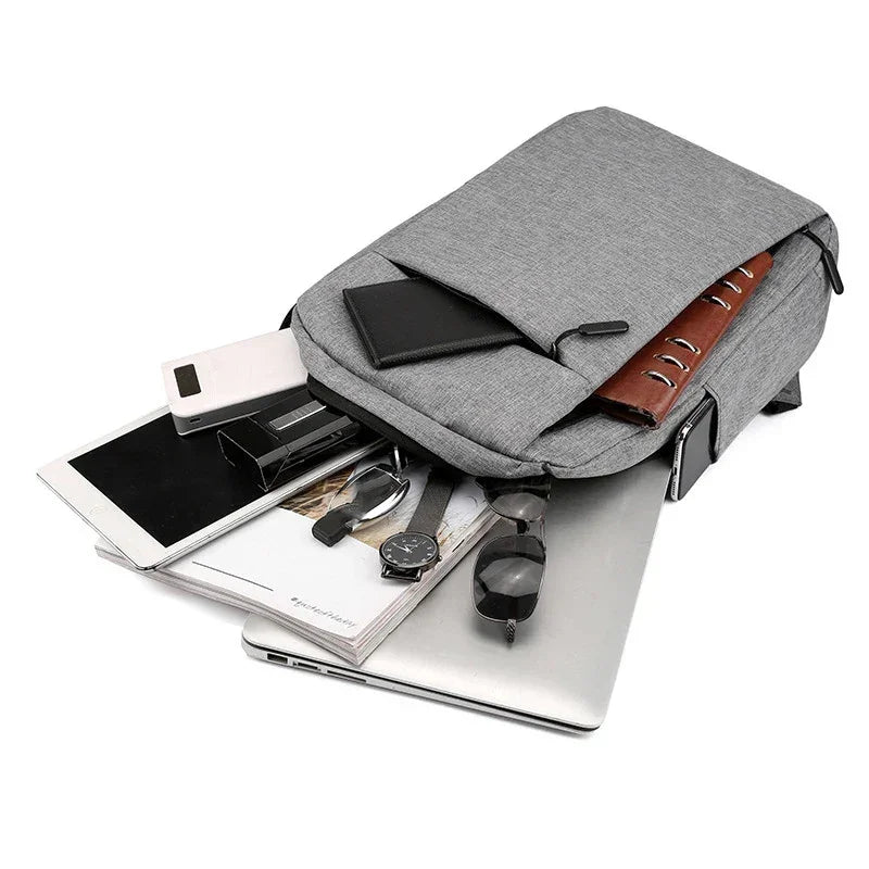 Gray backpack with items like a tablet and books on a white background