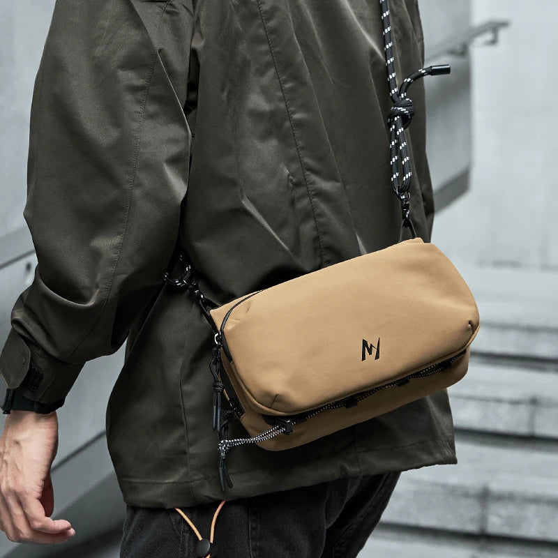 Man wearing the tan PeakCarry crossbody pack across his body on city steps