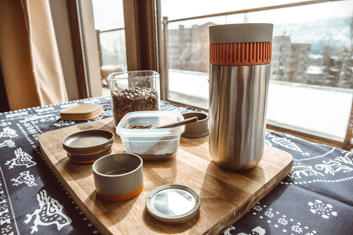 Portable vacuum pressure travel coffee maker on a wooden board with coffee grounds