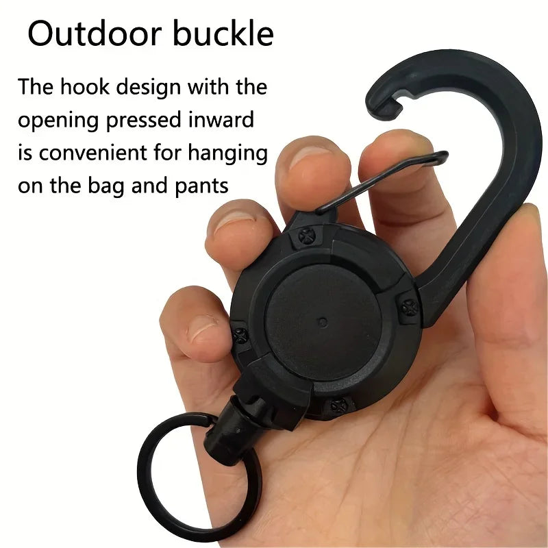 Hand holding a retractable key reel with an inward-opening carabiner for bags and belt loops
