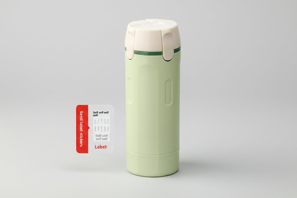 Green thermos bottle with beige lid and a small label sheet on a white background